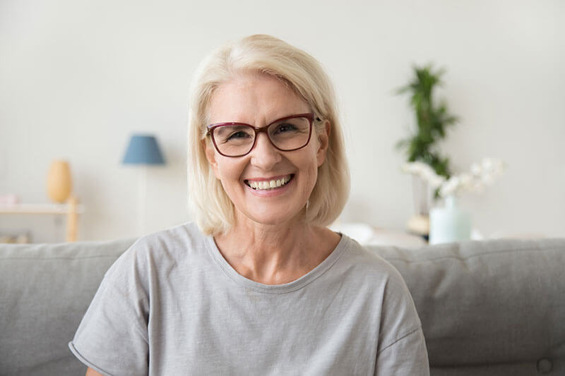 Older sitting on the couch and smiling